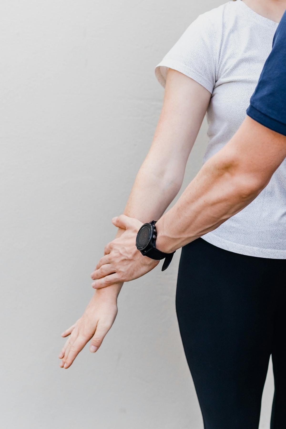 Therapeutin führt den Arm einer Patientin, Bewegungstest